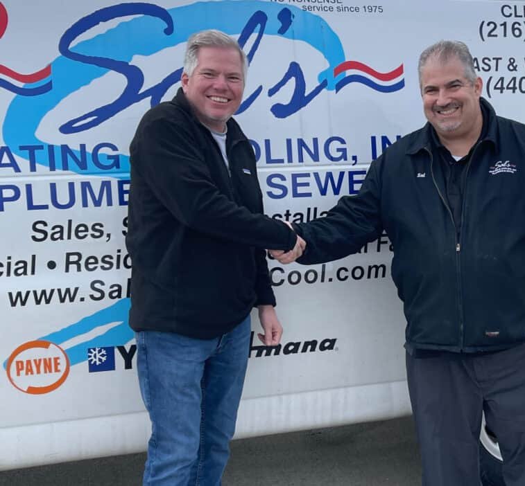 Two generations of Sal's shaking hands in front of a Sal's van