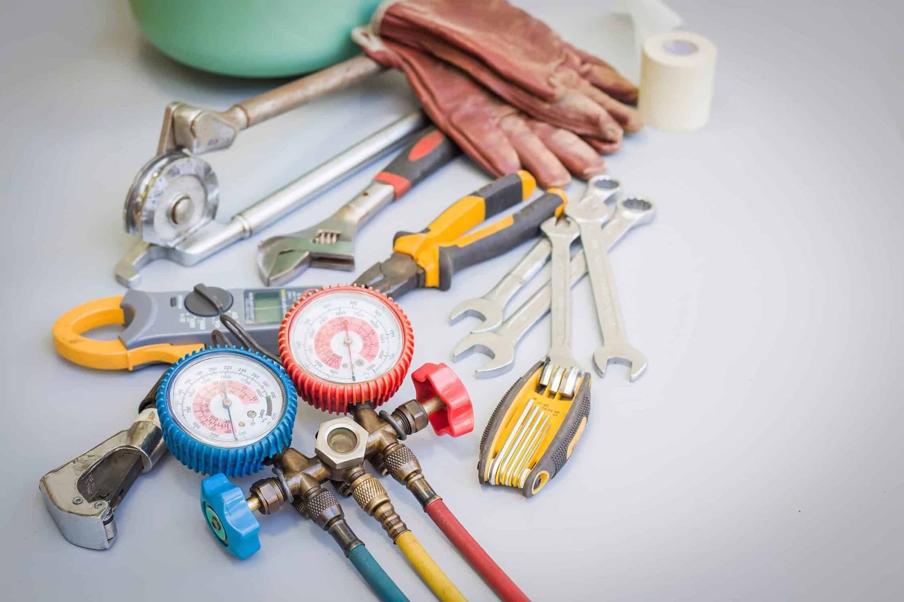 HVAC gauges, wrenches and gloves laid out for a tune-up